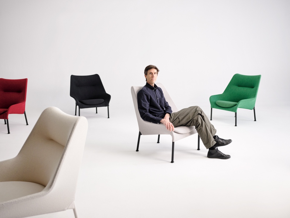 Mann sitzt entspannt im hellgrauen 02 Lounge Chair Sessel von Hay, weitere Sessel in rot, schwarz, grün und creme.