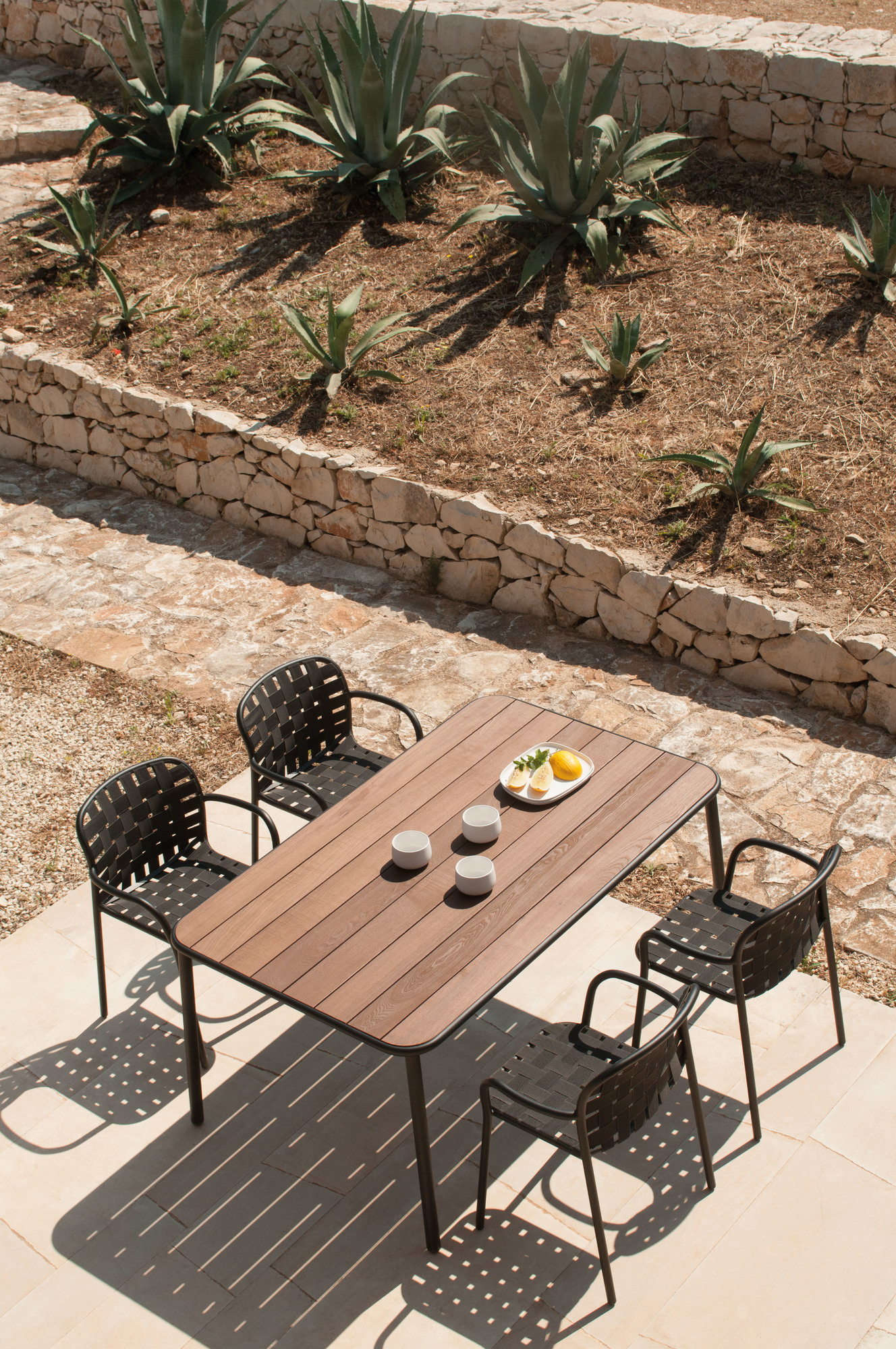 Yard Armlehnstuhl in Graugrün am Gartentisch mit Getränken und Zitronen, stilvolle Outdoor-Möbel für Garten und Terrasse.
