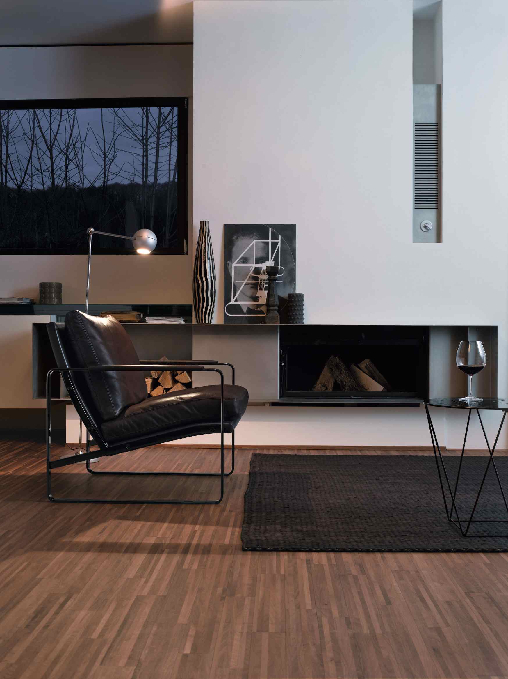 Schwarzer Ledersessel im Wohnzimmer mit Kamin. Walter Knoll Fabricius Sessel für stilvolles Wohnen.