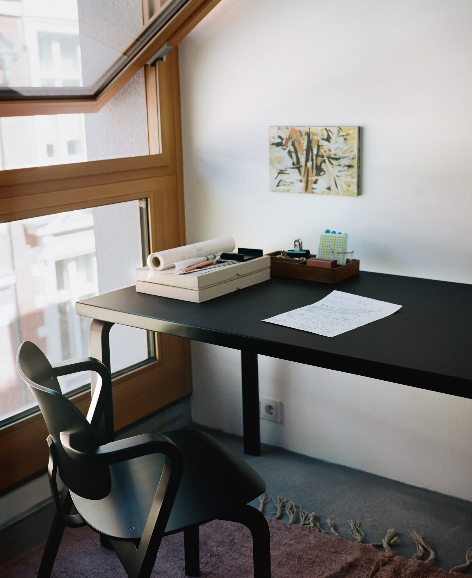 Schwarzer Aslak Chair Stuhl von Artek am Schreibtisch mit Büroartikeln und geöffnetem Fenster im Hintergrund.