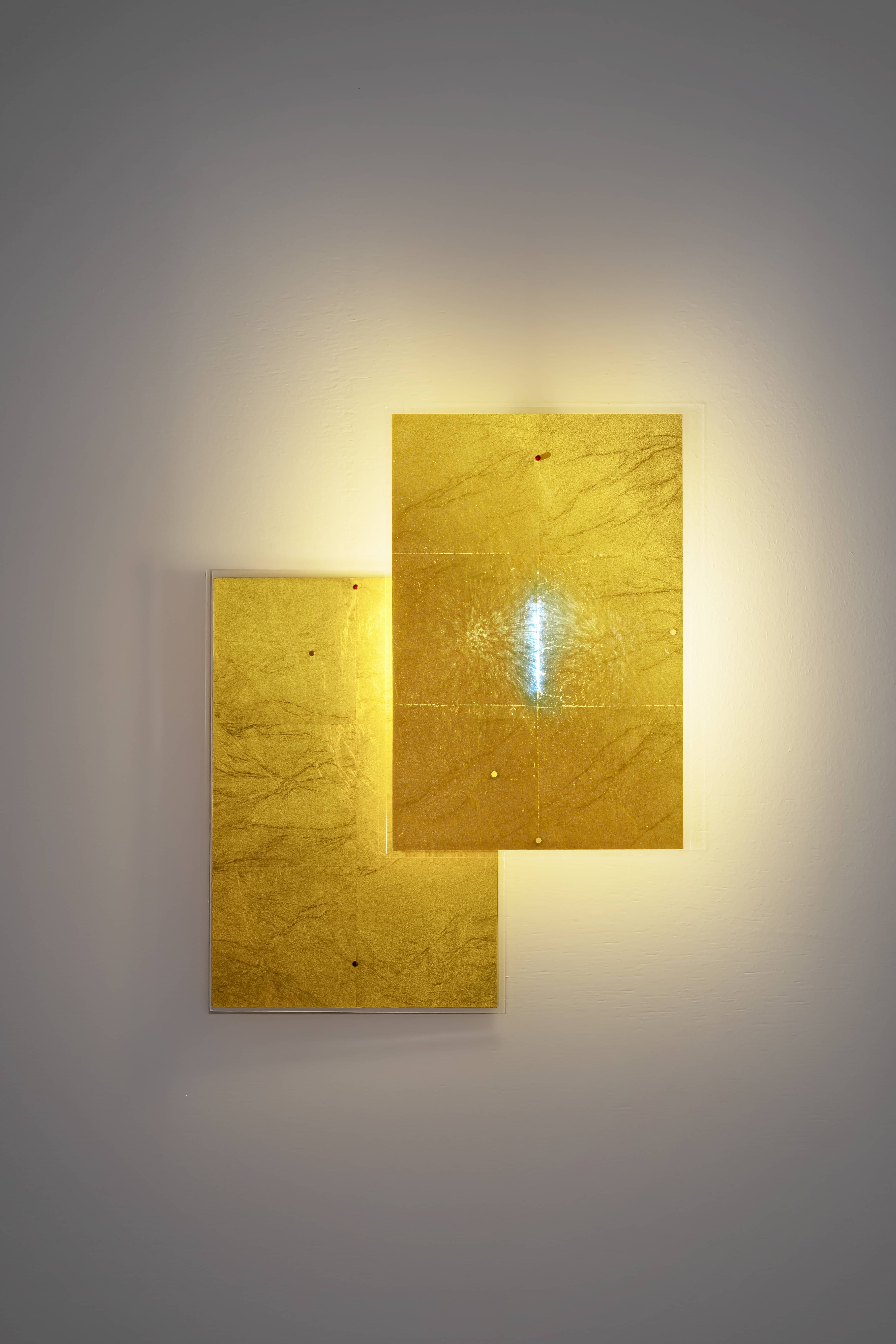 24 Karat Blau Wandleuchte von Ingo Maurer: Goldene, rechteckige Wandlampe mit bläulichem Licht.