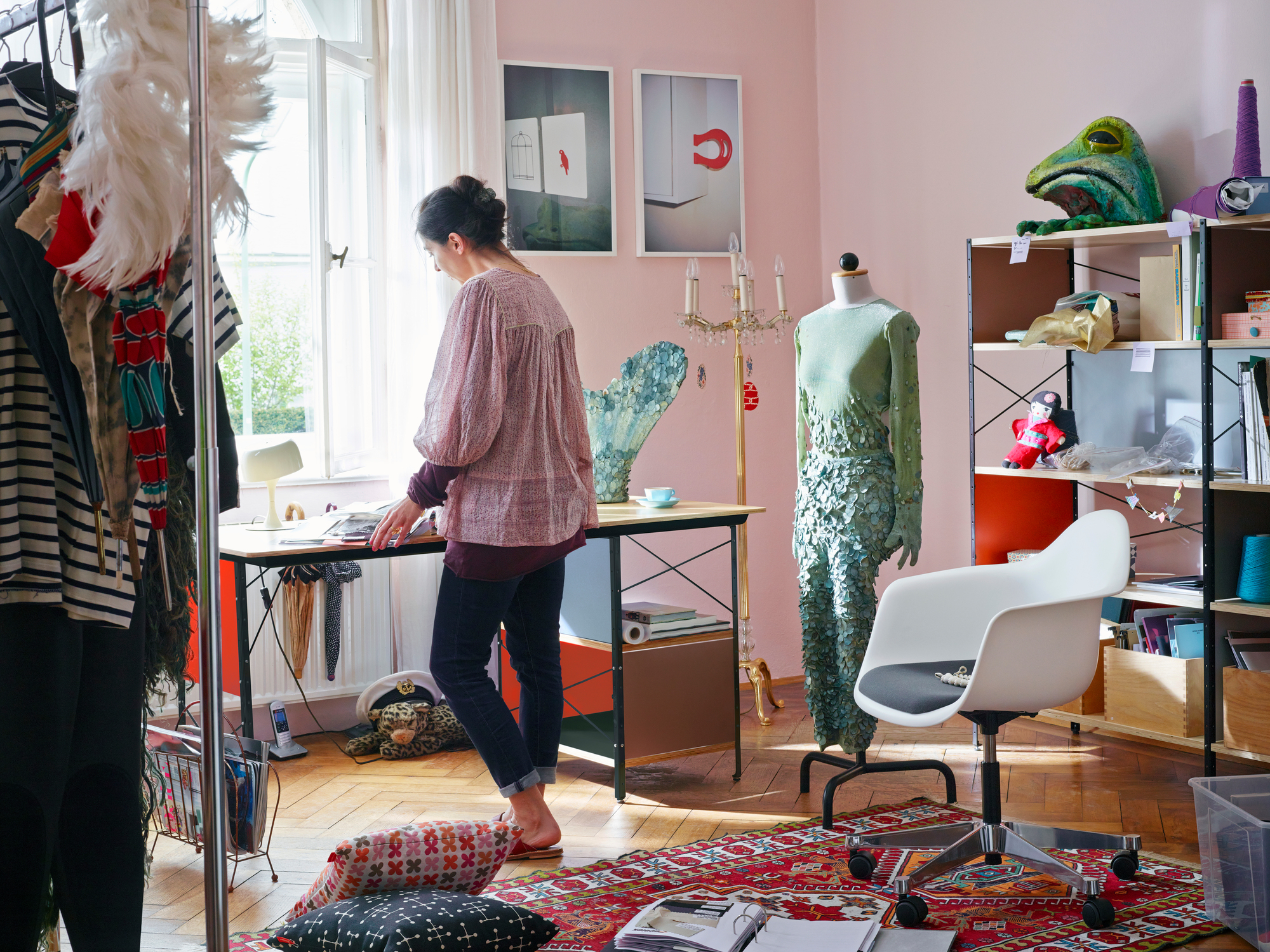 Ein Eames Desk Unit Schreibtisch in einem kreativen Arbeitszimmer mit Frau am Tisch.
