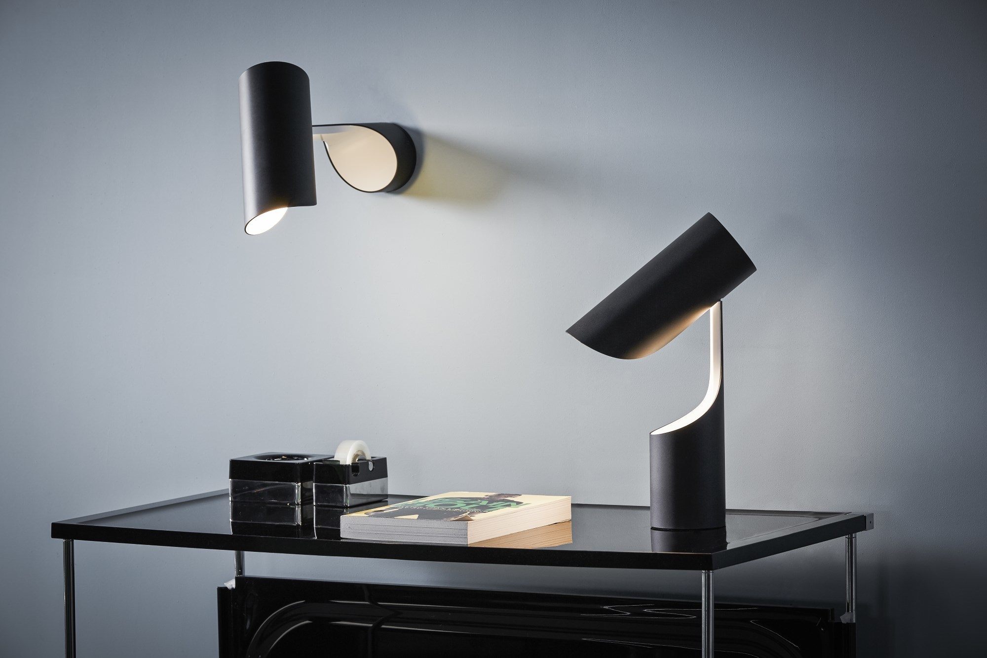 Schwarze Le Klint Mutatio Tischleuchte und Wandleuchte auf einem schwarzen Tisch, modernes Design.