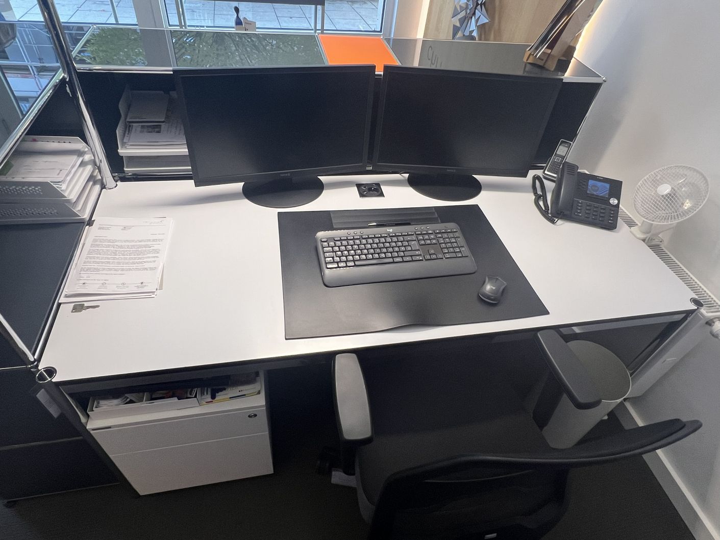 USM Haller Theke, gebrauchtes Büromöbel mit zwei Monitoren, Tastatur, Telefon und Bürostuhl im modernen Büro.