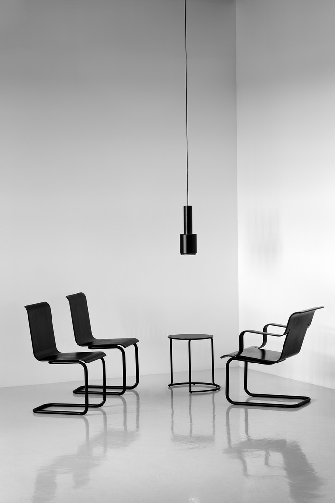Schwarzer Artek 606 Beistelltisch mit minimalistischen Stühlen und Hängelampe in einem modernen, hellen Raum.