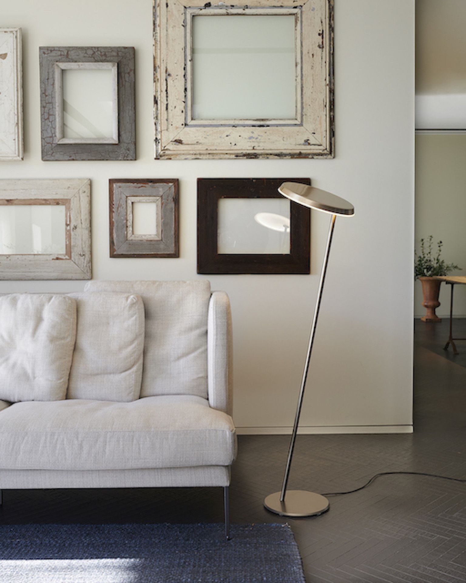 Moderne Stehlampe mit LED-Leuchte neben Sofa im Wohnzimmer, elegantes Design für stilvolle Beleuchtung.