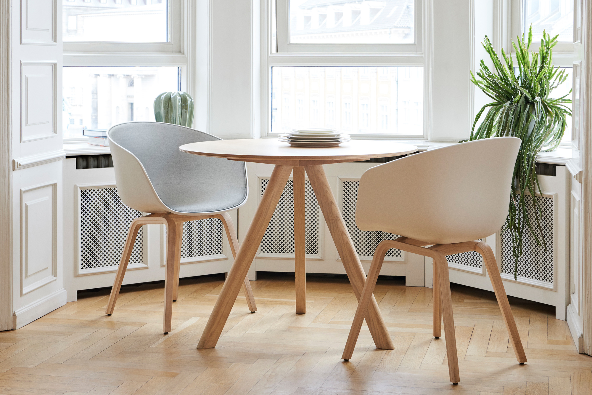 Heller Raum mit Copenhague Table CPH 20 Esstisch von Hay, runder Holztisch mit Design Stühlen.