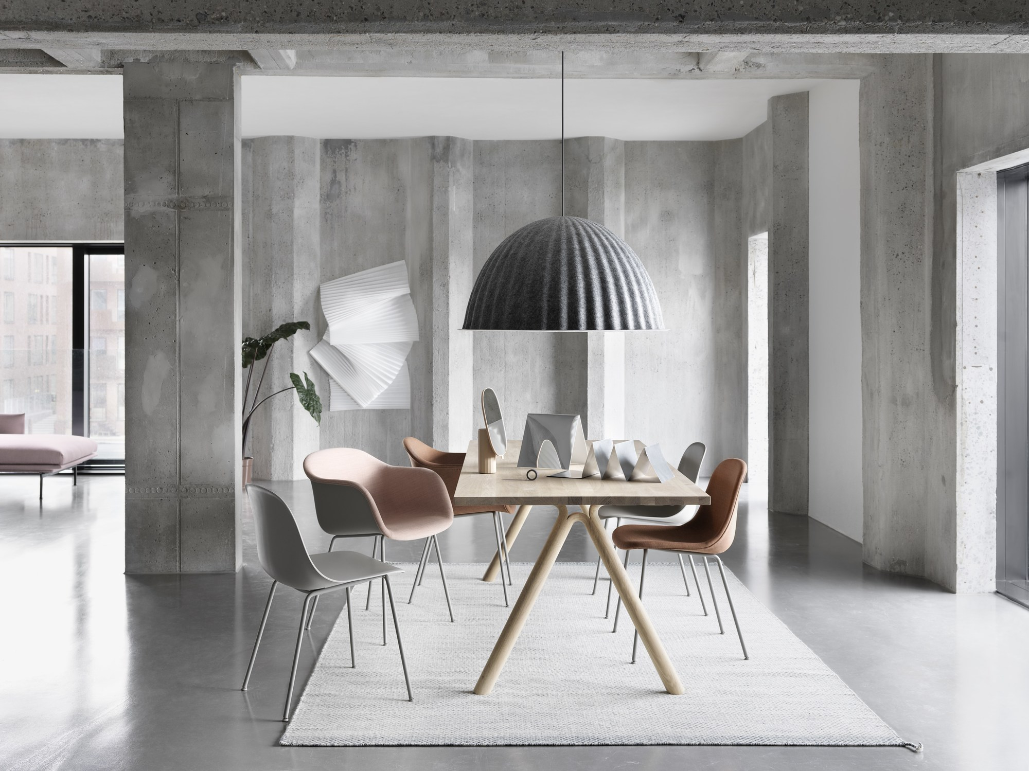 Graue Under The Bell Pendelleuchte von Muuto über Esstisch mit Stühlen in modernem Interieur.