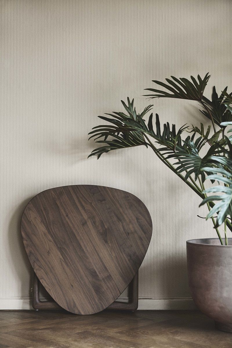 AndTradition Drop Leaf HM5 Beistelltisch aus Nussbaumholz, zusammengeklappt an der Wand, neben einer Zimmerpflanze.