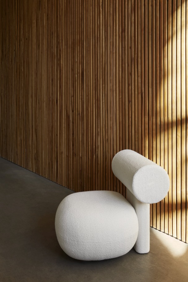 Hippo Lounge Chair Sessel von NORR11, vollgepolstert in Weiß, modernes Design vor Holzpaneelwand.
