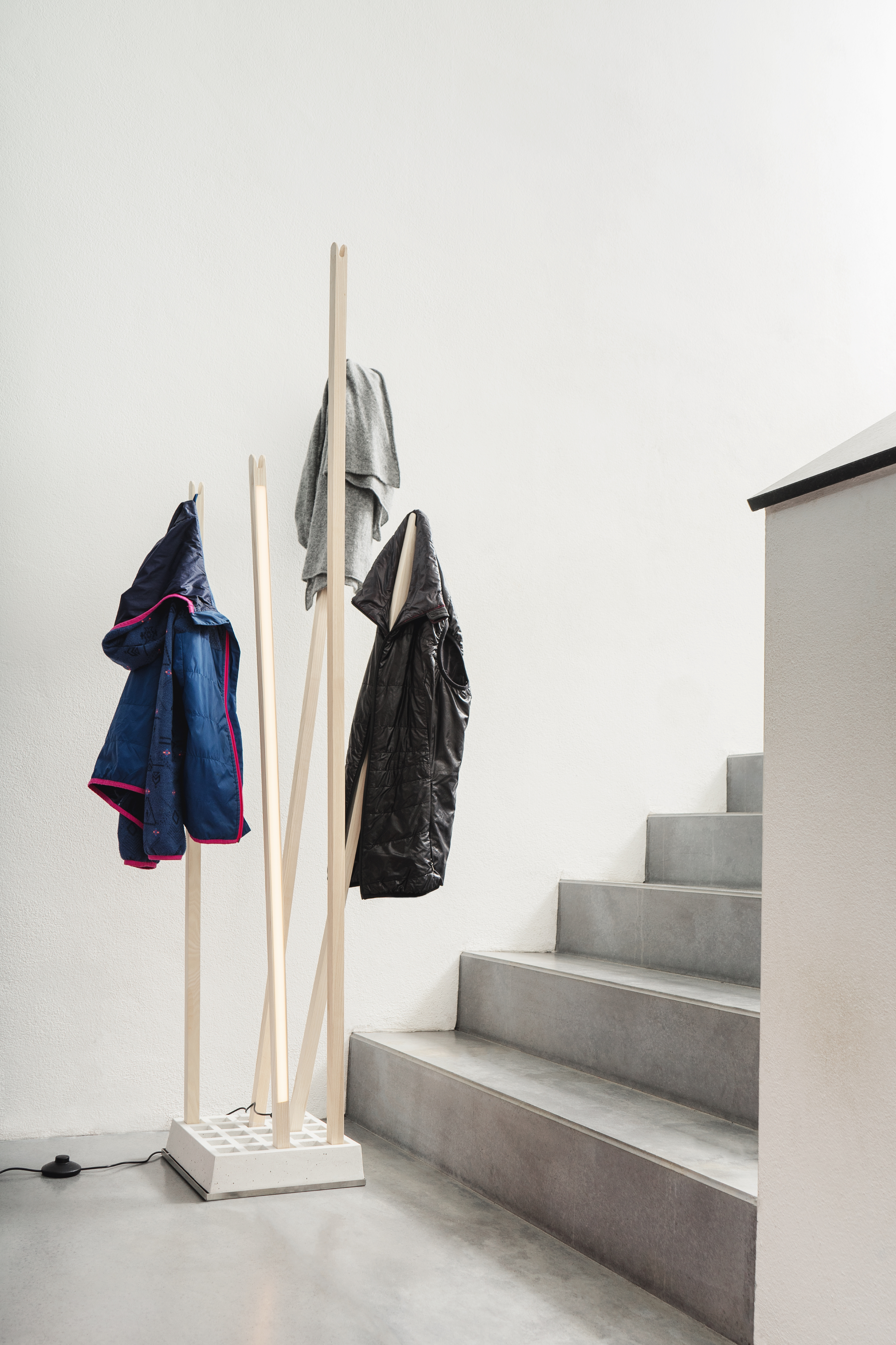Helle Pin Coat Garderobe von Nils Holger Moormann mit integrierter Pin Light Leuchte und Jacken im Flur.