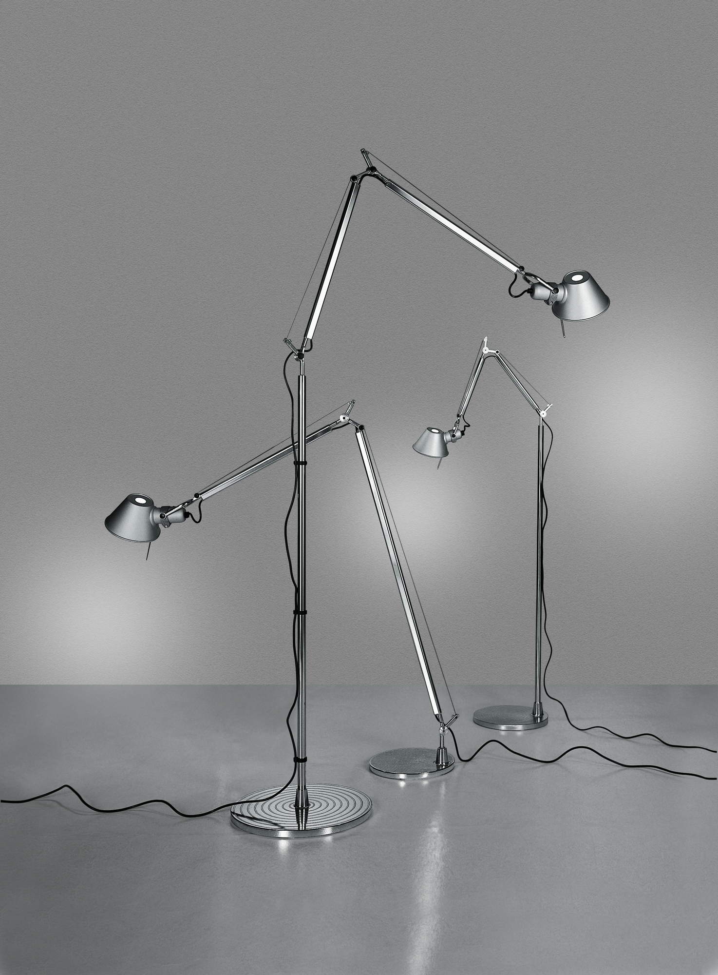 Drei moderne, silberne Tolomeo Stehleuchten von Artemide mit verstellbaren Armen und konischen Lampenschirmen.