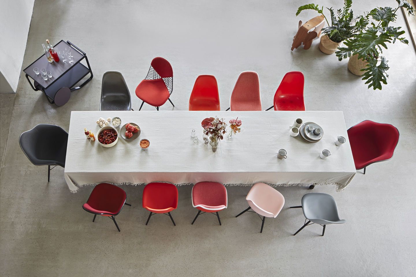Esstisch mit verschiedenen Eames Plastic Arm Chairs, darunter ein schwarzer Vitra DAR Stuhl, von oben fotografiert.