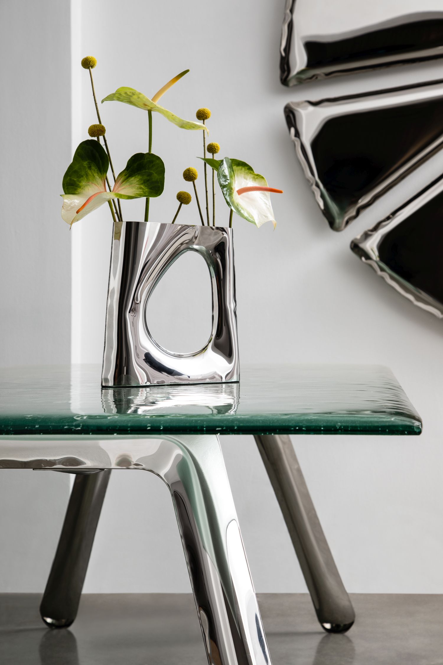 Nogi Tischgestell von Zieta mit Glasplatte und Blumen in einer silbernen Vase.