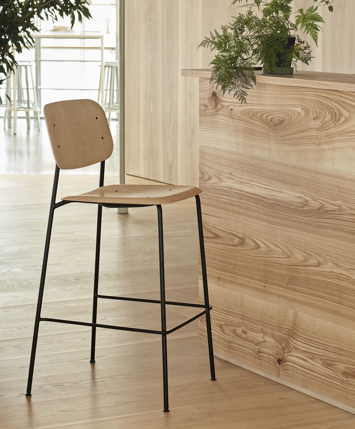 Hay Soft Edge 90 Barhocker mit niedrigem Gestell, Sitzfläche aus hellem Holz und schwarzem Metallgestell.