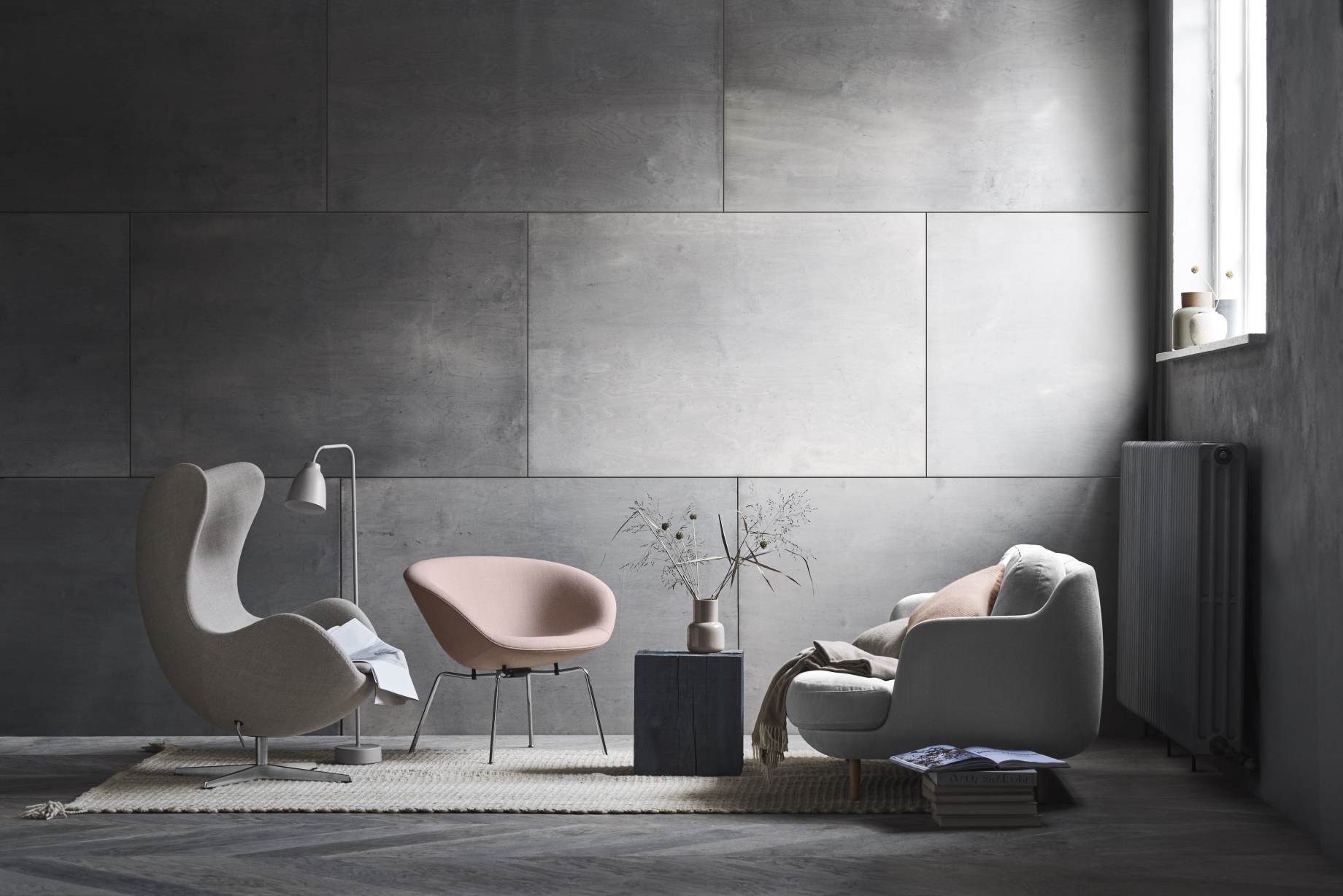 Wohnzimmer-Szene mit Fritz Hansen Pot Sessel in Rosa und grauem Egg Chair auf einem Teppich.