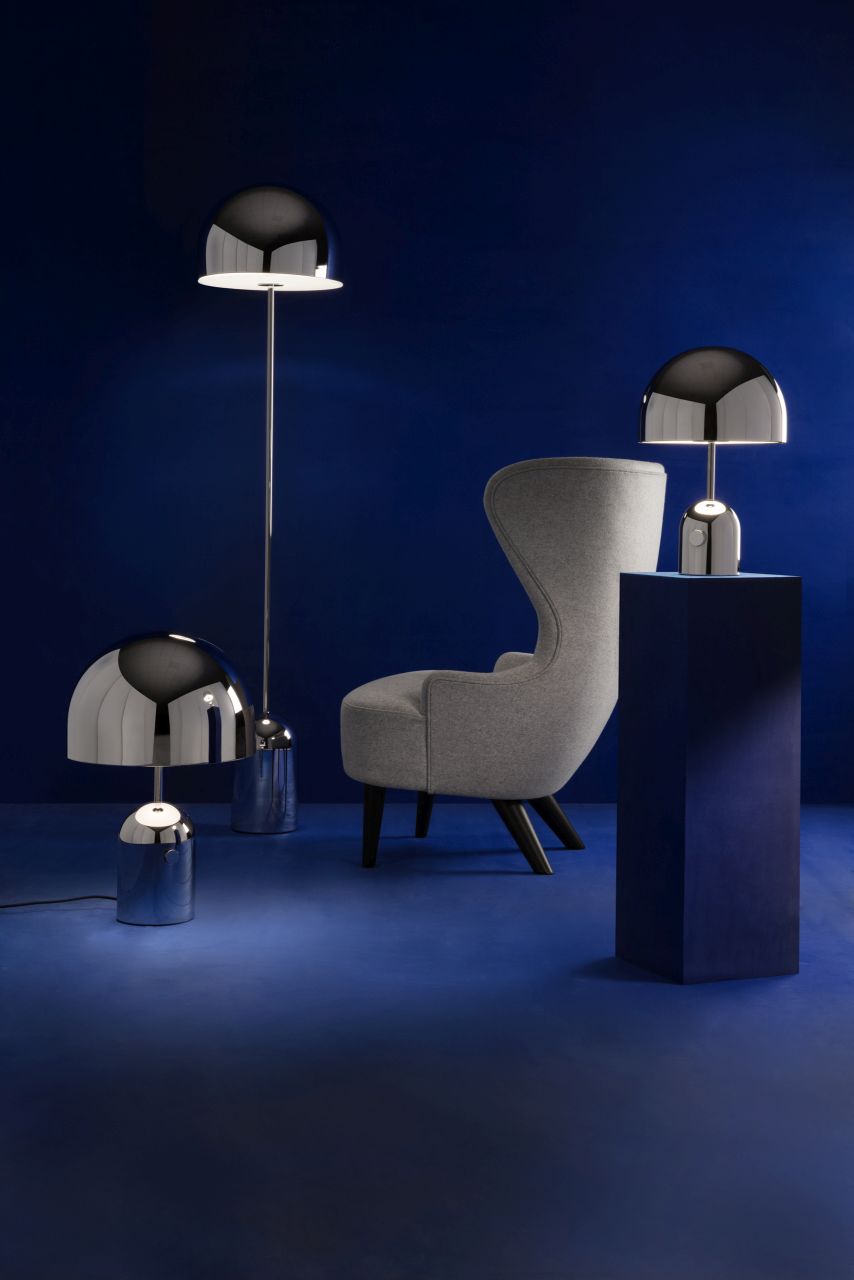 Bell Tischleuchte LED von Tom Dixon, silberne Design-Leuchten und Sessel vor blauem Hintergrund.