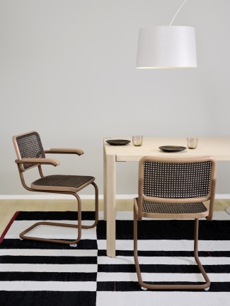 S 64 V Thonet Freischwinger Stühle aus Stahlrohr mit Wiener Geflecht an Esstisch auf Teppich.