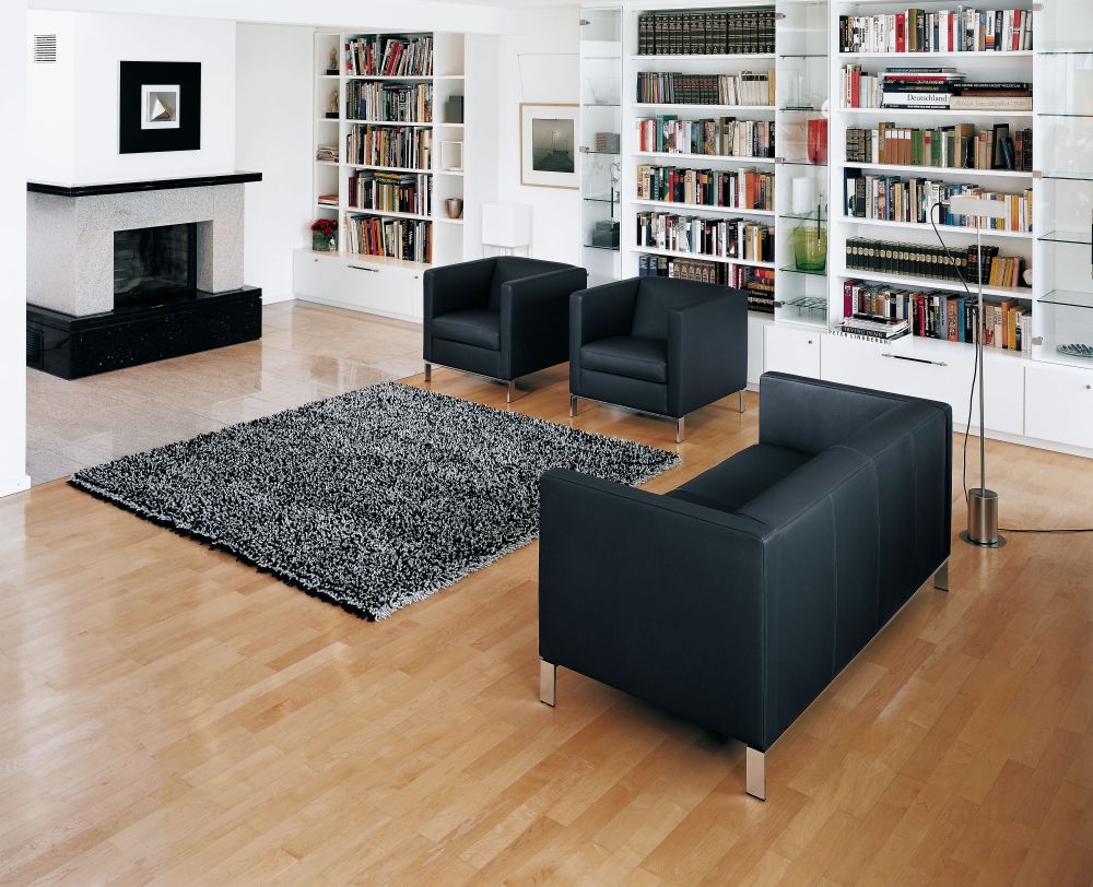 Innenaufnahme: Zwei schwarze Walter Knoll Foster Sessel und ein Sofa im modernen Wohnzimmer.