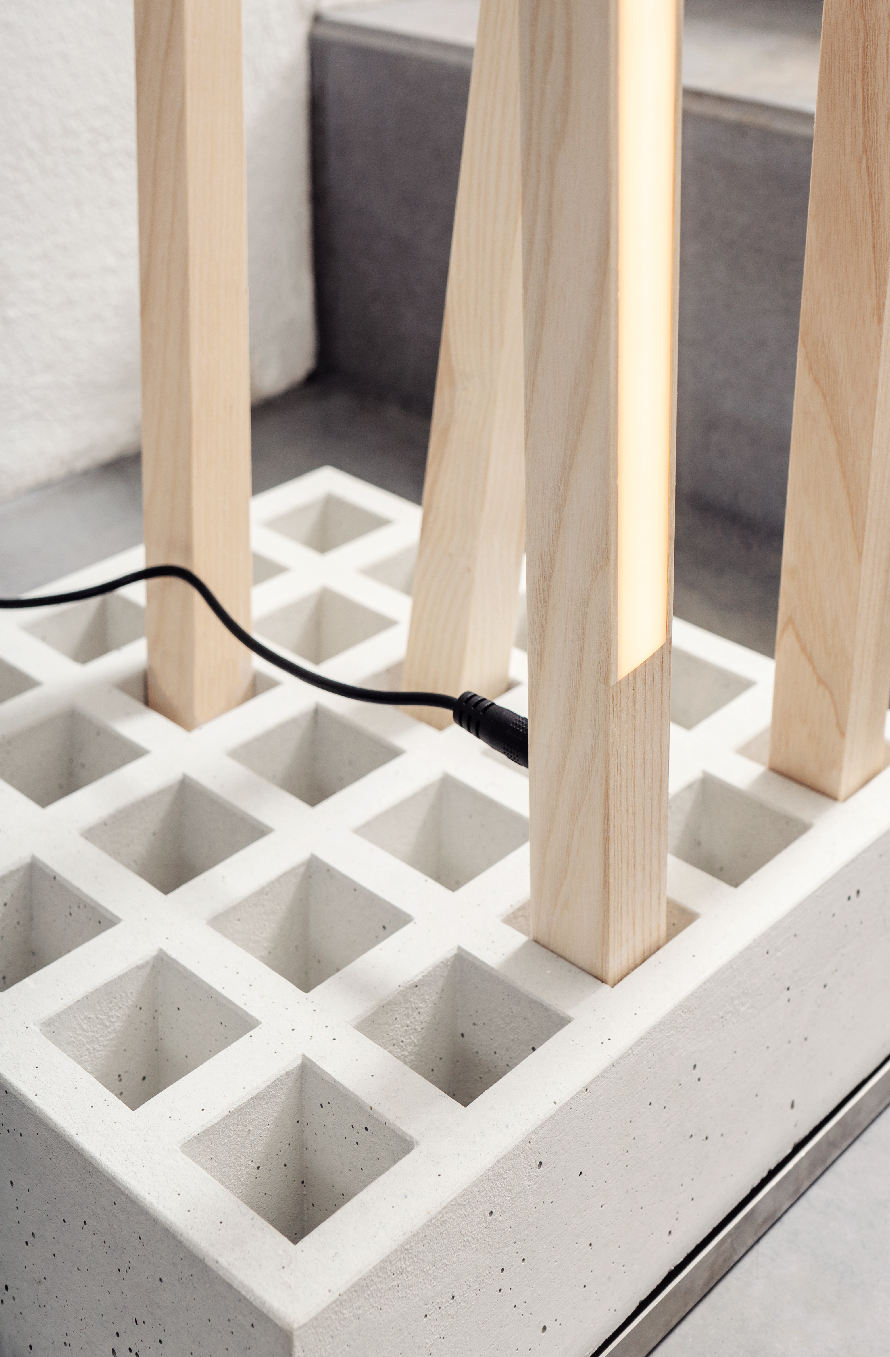 Detailaufnahme der Moormann Pin Light Leuchte: Moderne Lampe mit Holzstäben und Betonfuß, minimalistisches Design.