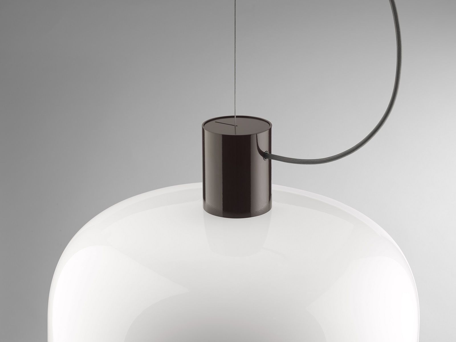 Detailaufnahme der Bellhop Pendelleuchte von Flos, weiße Glaskuppel und braune Aufhängung.