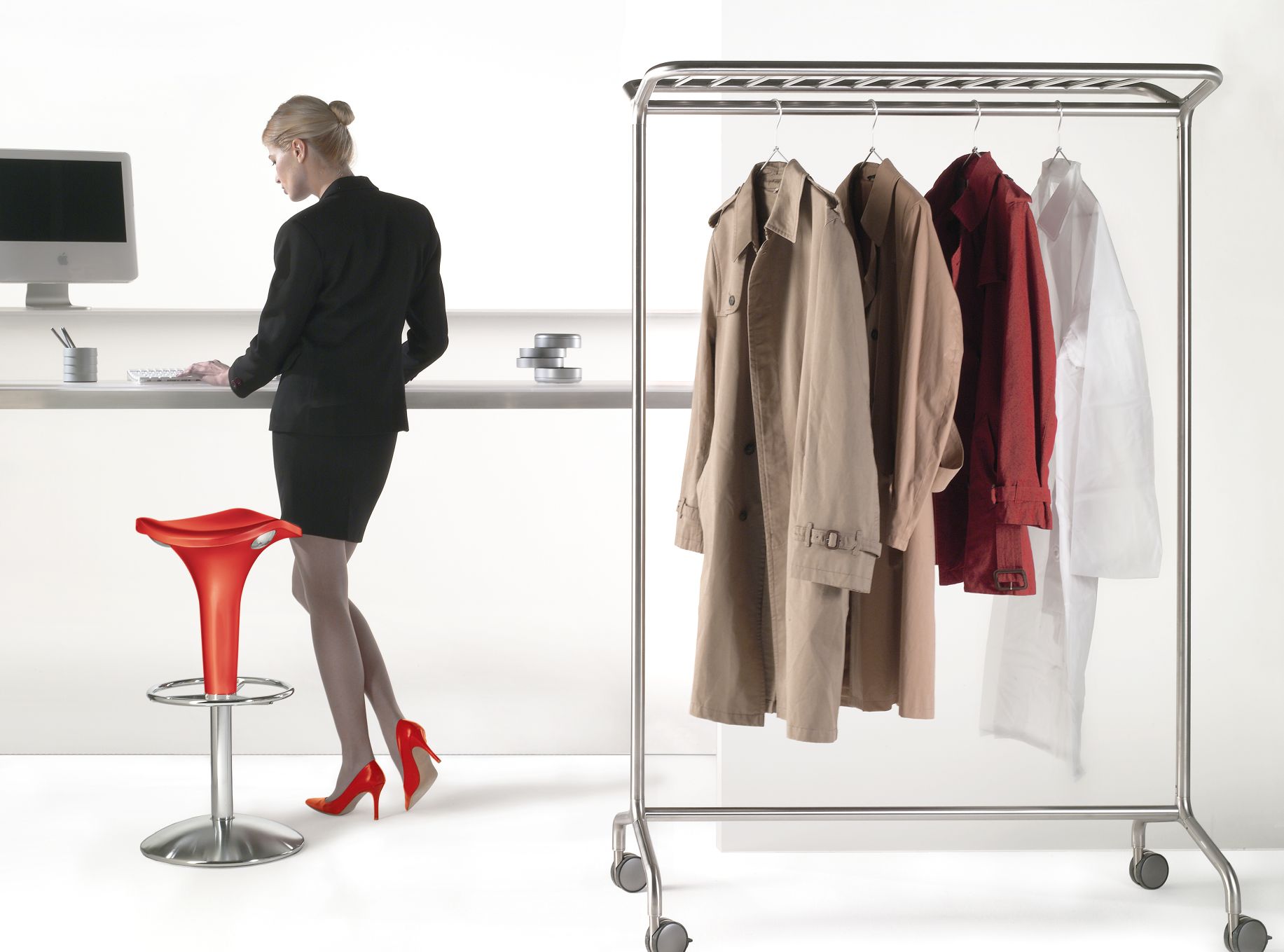 Nox Vesta Kleiderbügelständer von Rexite mit Kleidung und Frau im Bürooutfit im Hintergrund.