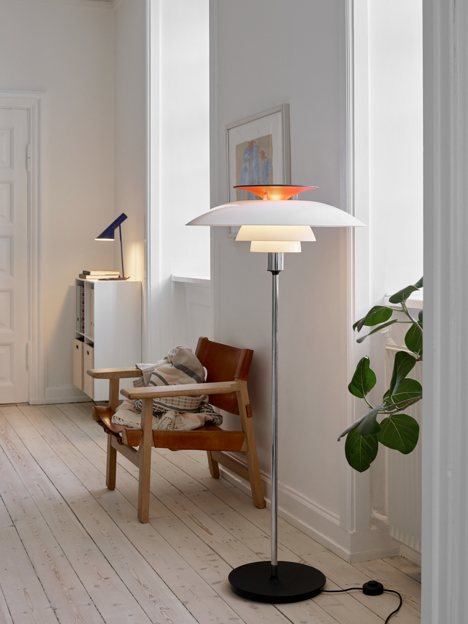 PH 80 Stehleuchte von Louis Poulsen in modernem Wohnzimmer mit Sessel und Pflanze.