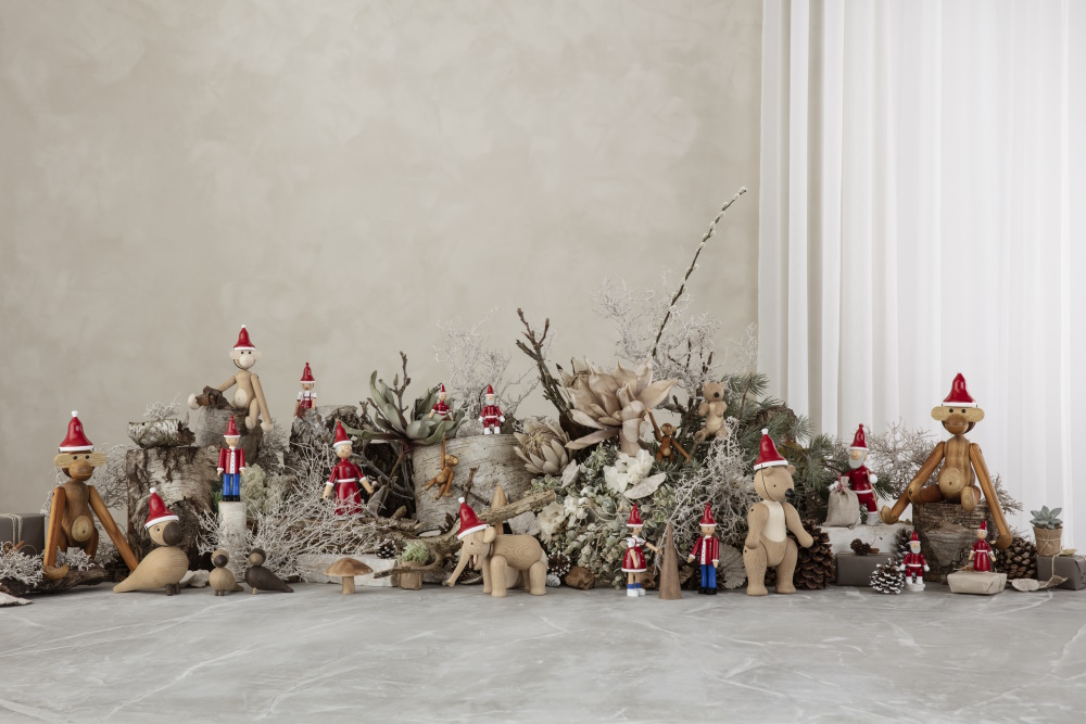 Holzfiguren mit Weihnachtsmützen: Affen, Elefant, Bär, Vögel und Wichtel als festliche Weihnachtsdekoration.