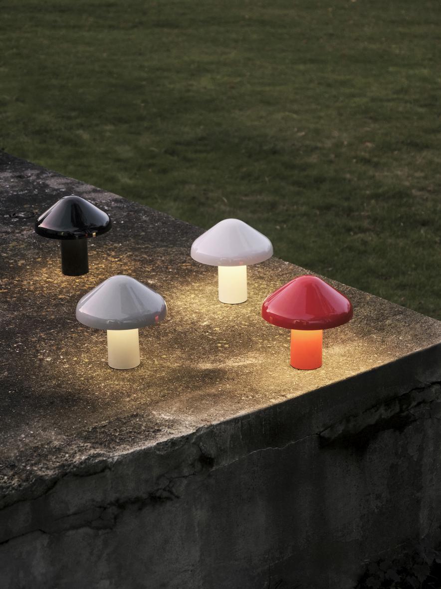 Mehrere Pao Portable Lamp Akkuleuchten von Hay in verschiedenen Farben auf einer Betonfläche.