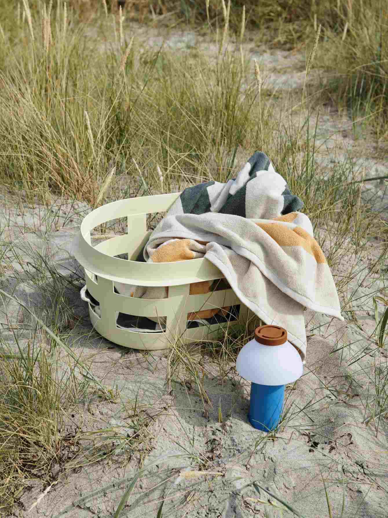 Blauer Hay Wäschekorb S RECYCLED mit Handtüchern auf Sand, ideal für Bad oder Schlafzimmer.