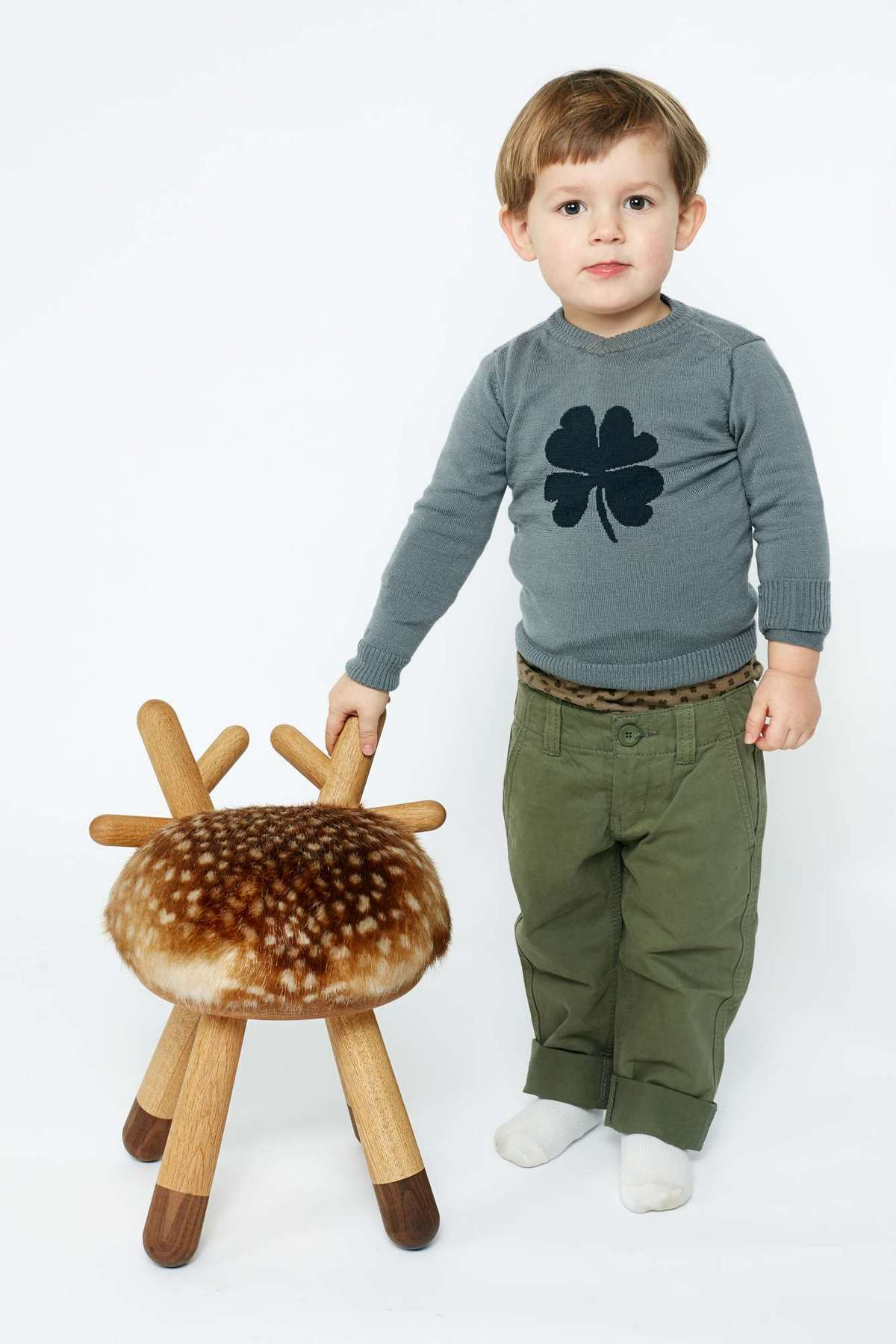 Kleiner Junge steht neben Bambi Kinderstuhl EO  mit Fellimitat und Holzbeinen.