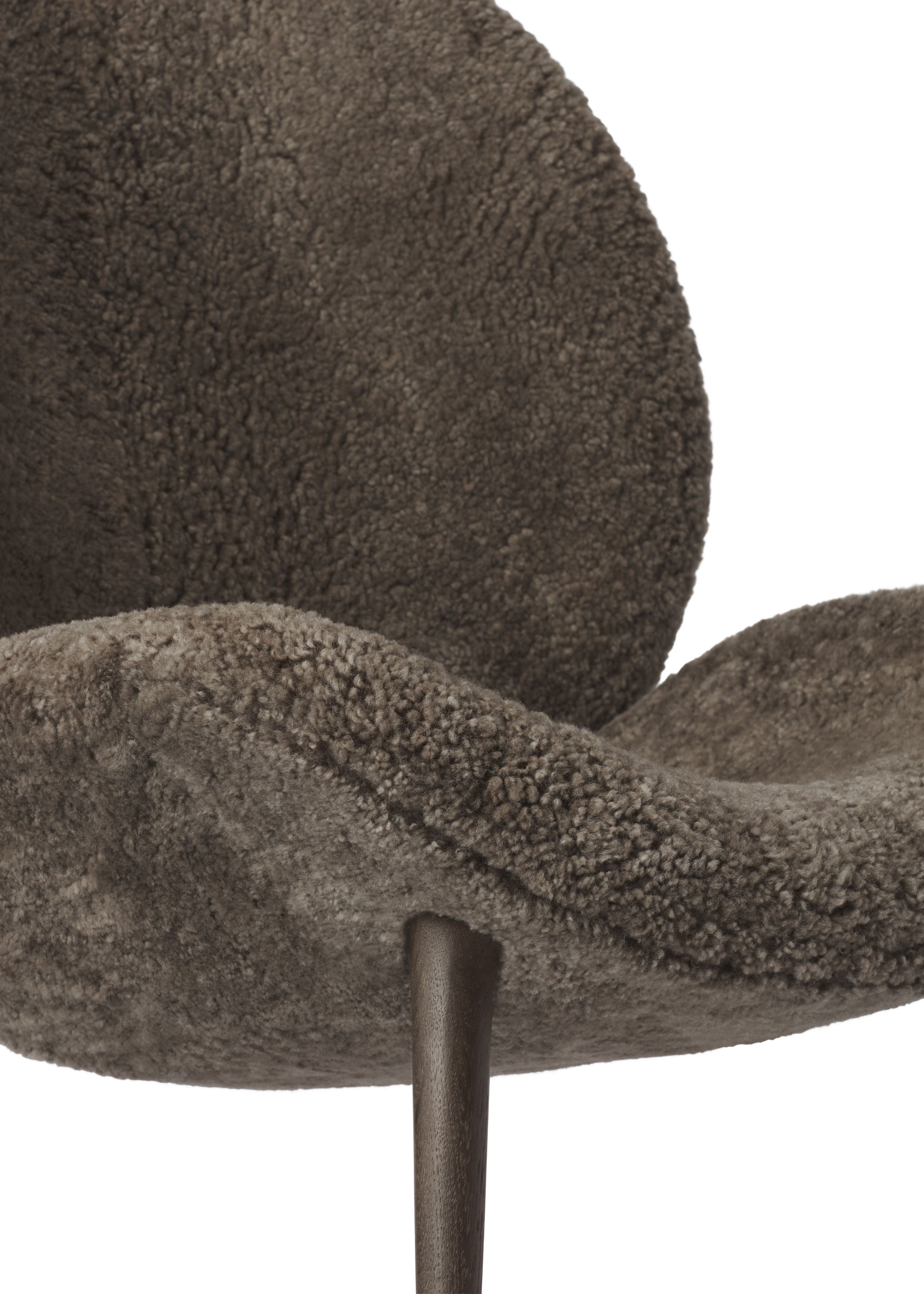 Detailaufnahme des Vipp Lodge Loungestuhls mit braunem, flauschigem Schaffellbezug und dunklen Holzbeinen.