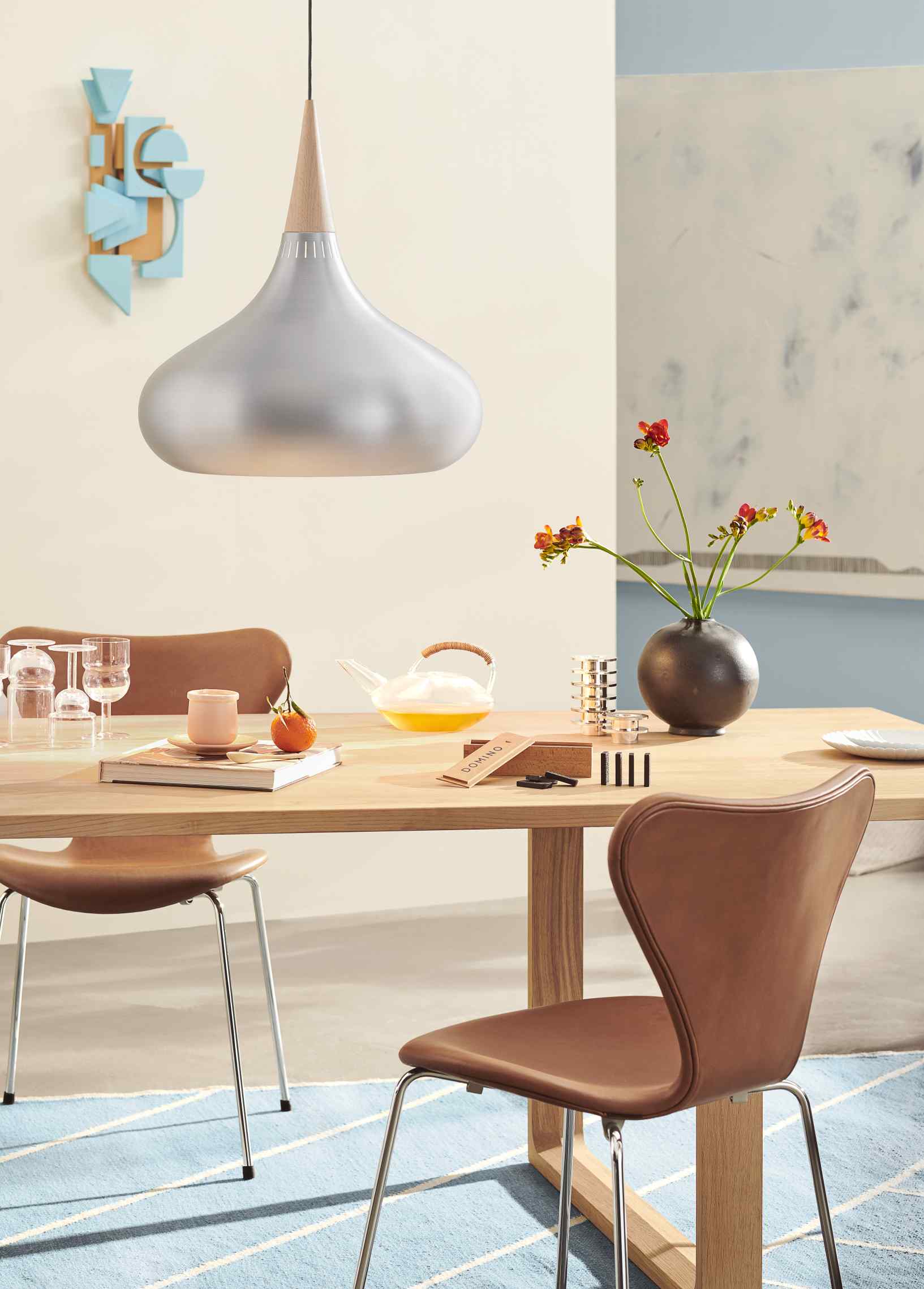 Essay Tisch von Fritz Hansen in heller Holzoptik mit Stühlen und dekorativen Gegenständen.