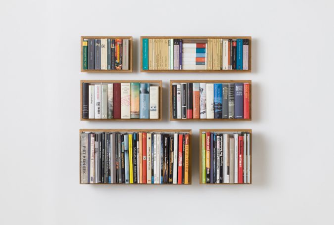 Sechs kleine, quadratische Eiche Regale an einer weißen Wand, gefüllt mit Büchern.