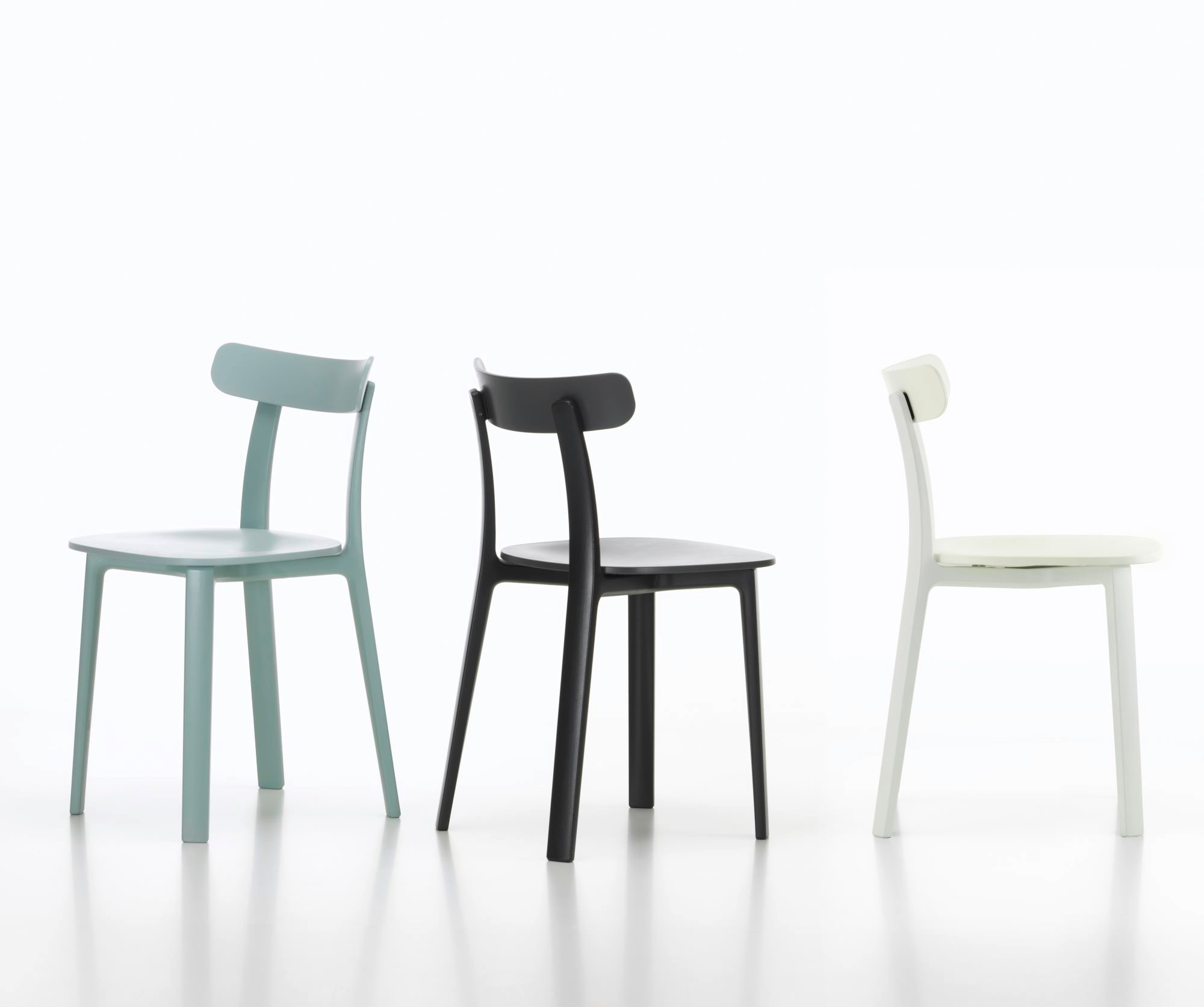 Drei Vitra All Plastic Chairs Outdoor in blau, schwarz und weiß vor weißem Hintergrund.