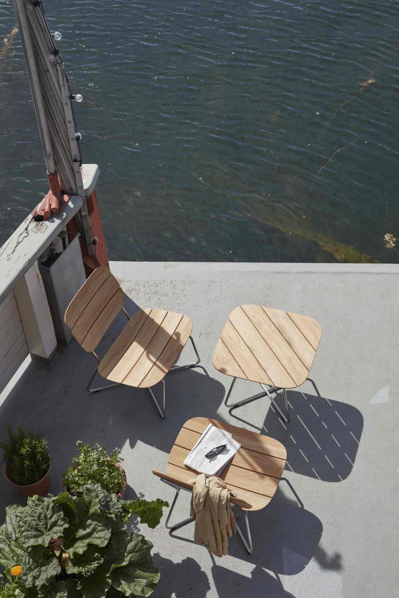 Lilium Lounge Chair von Skagerak: Outdoor Stuhl aus Teakholz mit Stahlgestell auf Terrasse.
