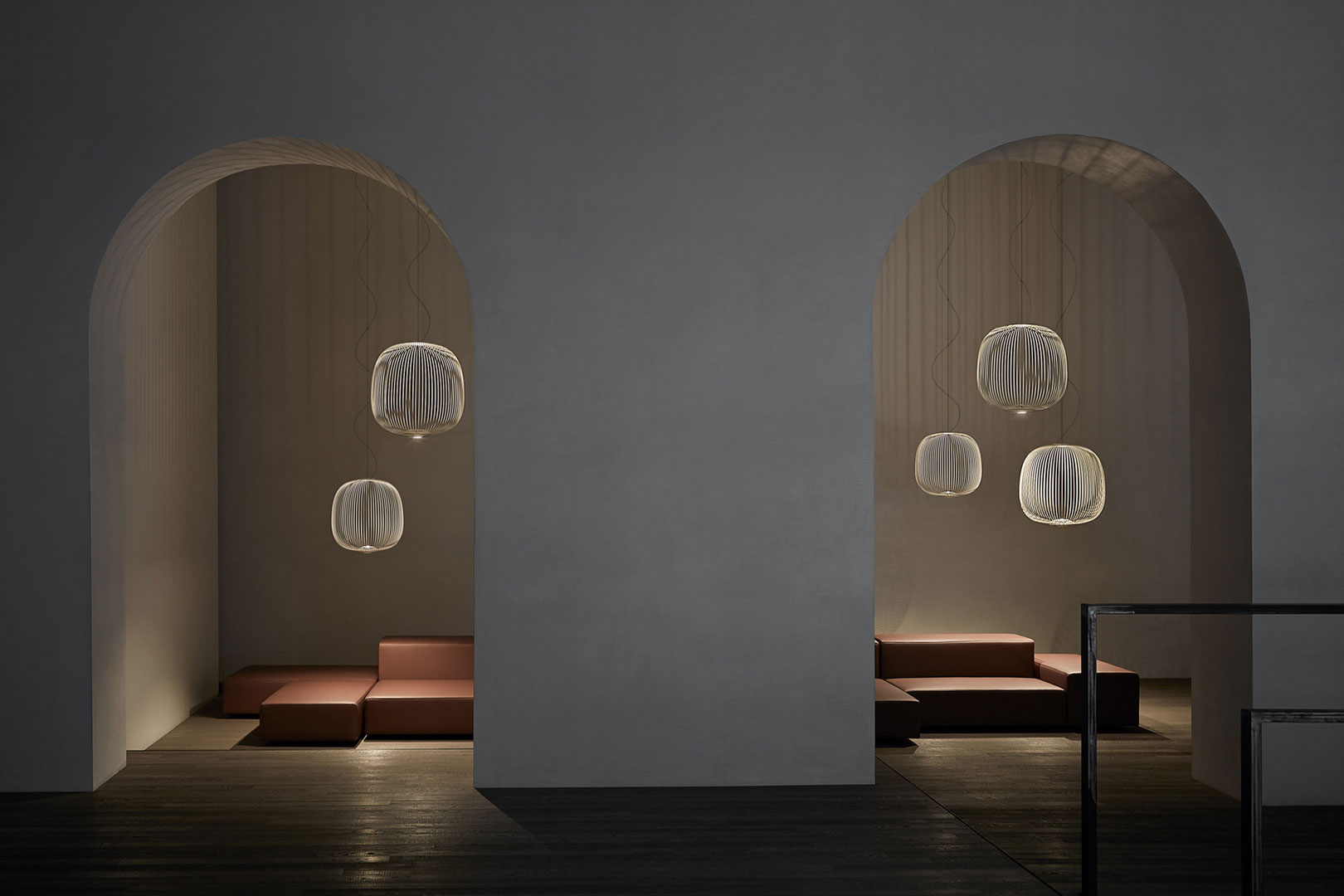 Mehrere Foscarini Spokes Pendelleuchten in Schwarz hängen in einem modernen Raum.