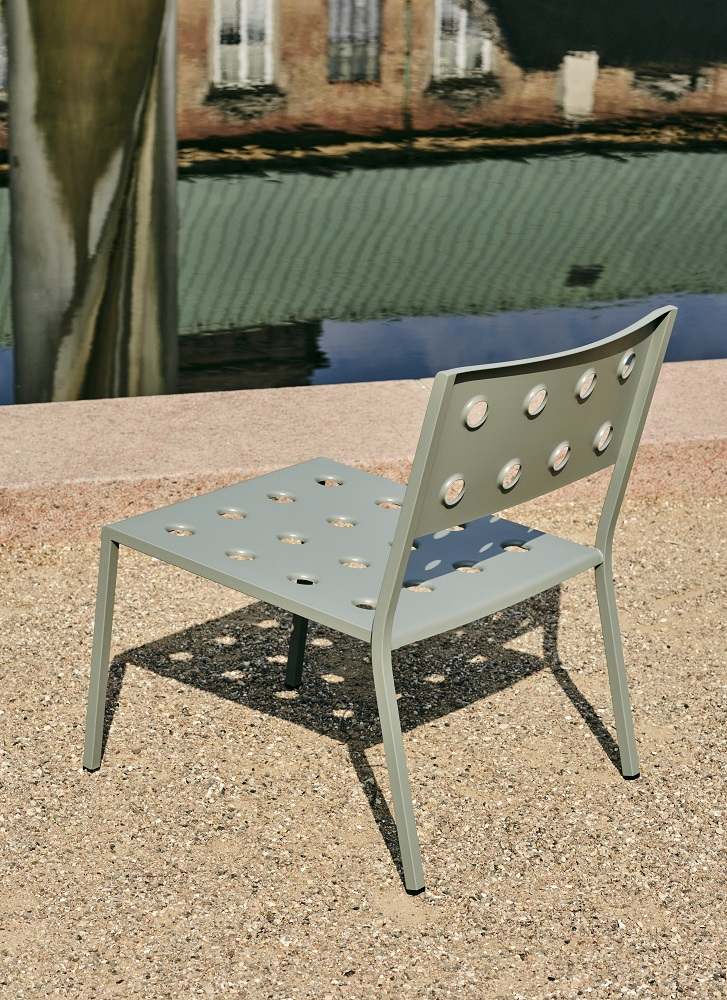 Grauer Hay Balcony Outdoor Lounge Chair Stuhl mit runder Lochmusterung vor Wasserfläche.