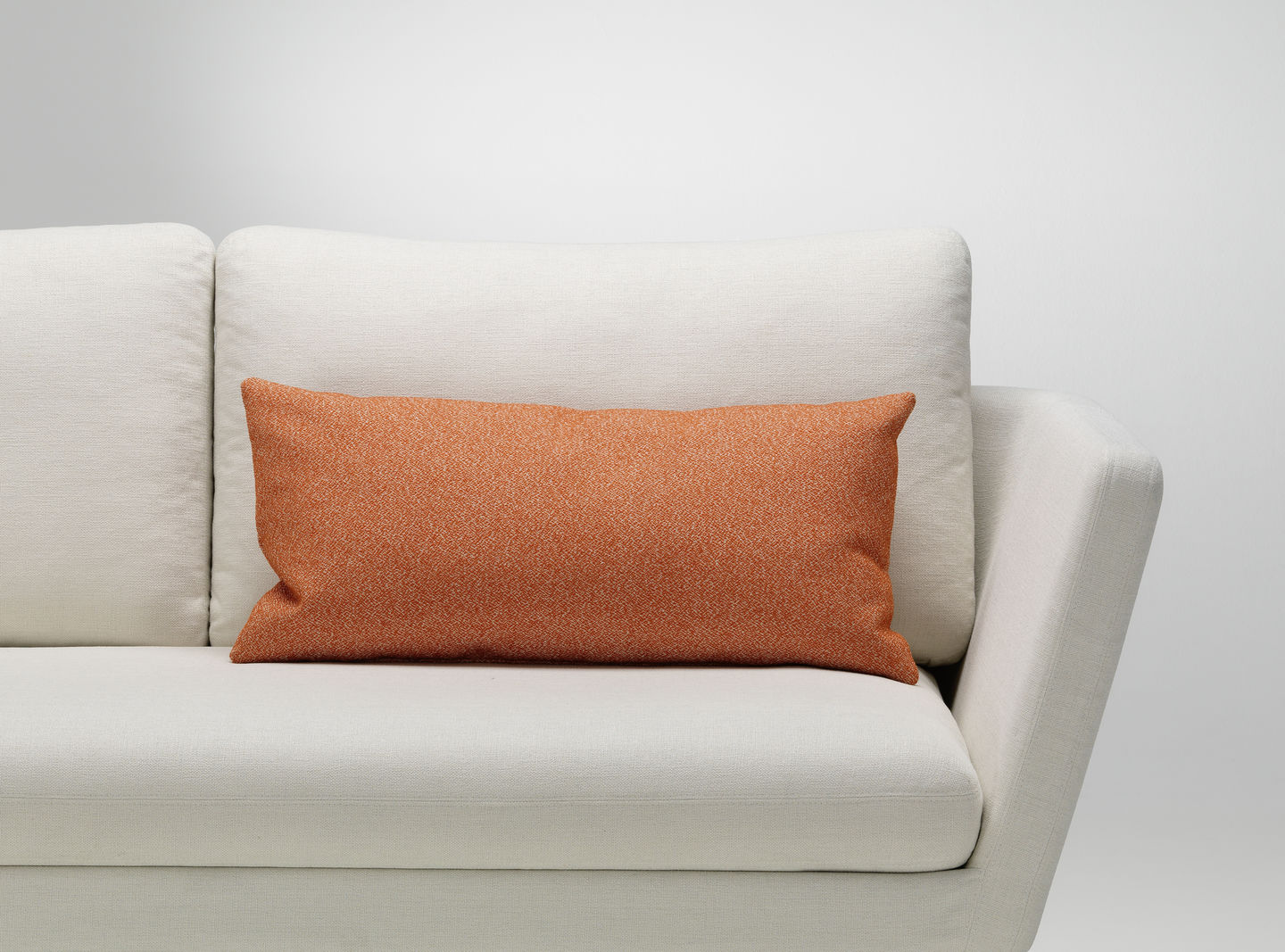 Orangefarbenes Vitra Kissen als Sofakissen auf einem weißen Sofa, modernes Wohnaccessoire für stilvolles Interieur.