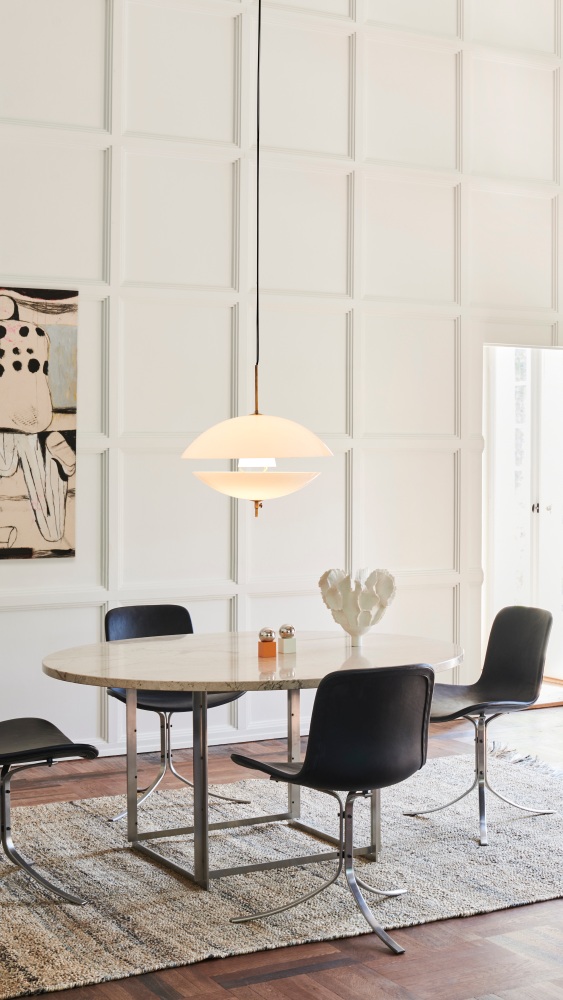 Helle Clam Pendelleuchte von Fritz Hansen über Esstisch mit Stühlen und Dekoration.