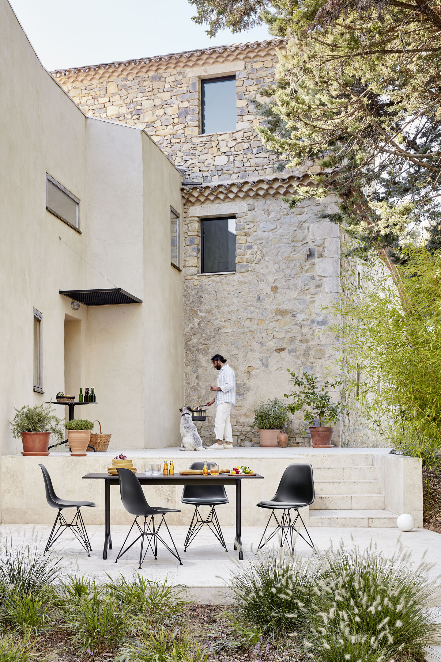Schwarzer Eames Plastic Side Chair DSR von Vitra am Esstisch im Außenbereich. Designklassiker mit Stahlgestell.