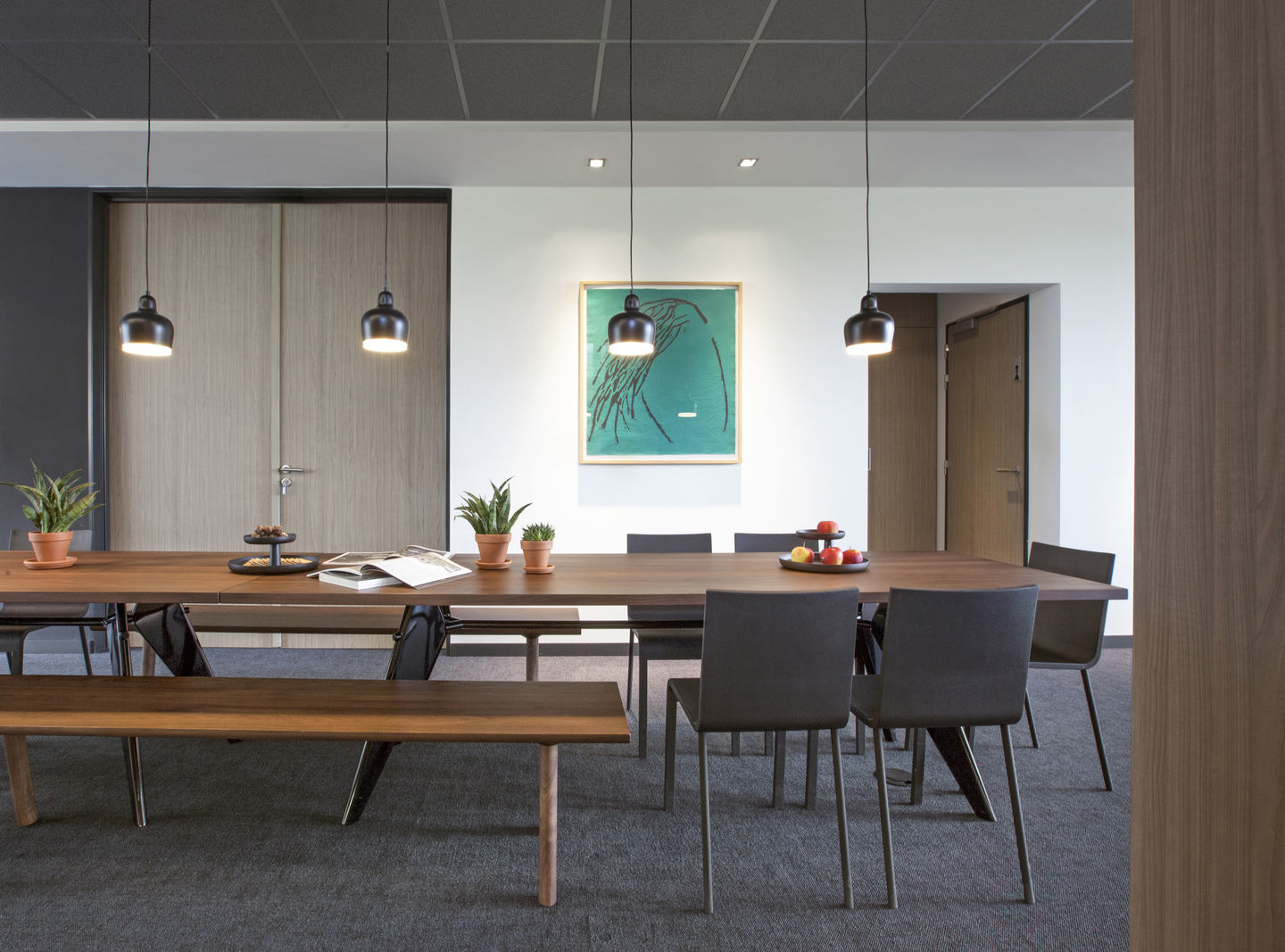 .03 Stuhl von Vitra an einem langen Holztisch mit passender Bank in einem modernen Büro.
