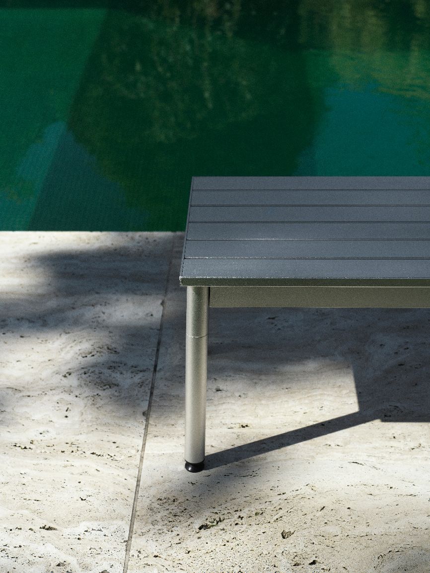 Detailaufnahme der grauen Normann Copenhagen Ex Bank Outdoor mit silbernen Beinen und Pool im Hintergrund.