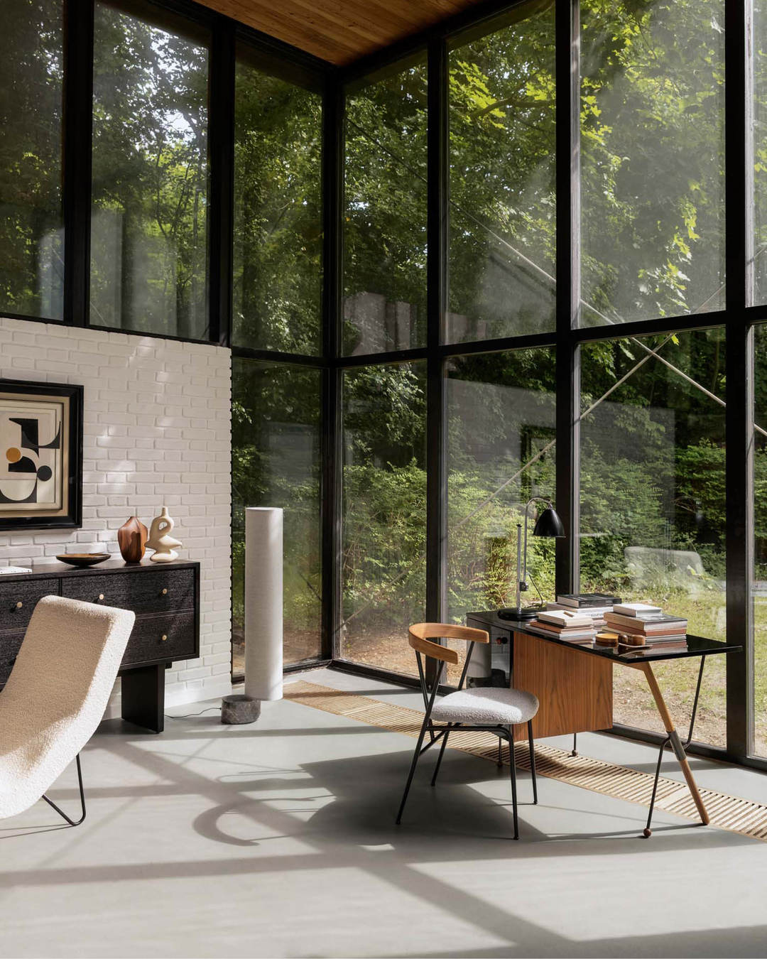 Heller Raum mit Gubi 62 Desk Schreibtisch mit Glasplatte und Holz, Stuhl und Bücher vor Fensterfront.