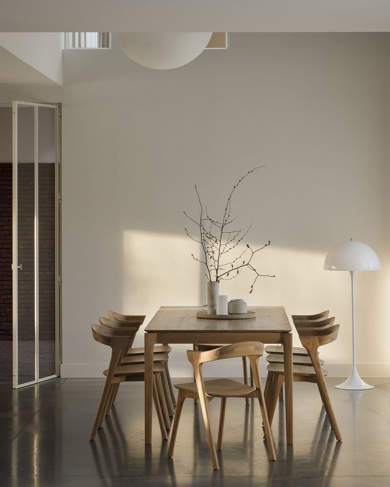 Esstisch aus Holz mit vier Stühlen und minimalistischer Dekoration in einem hellen, modernen Esszimmer.