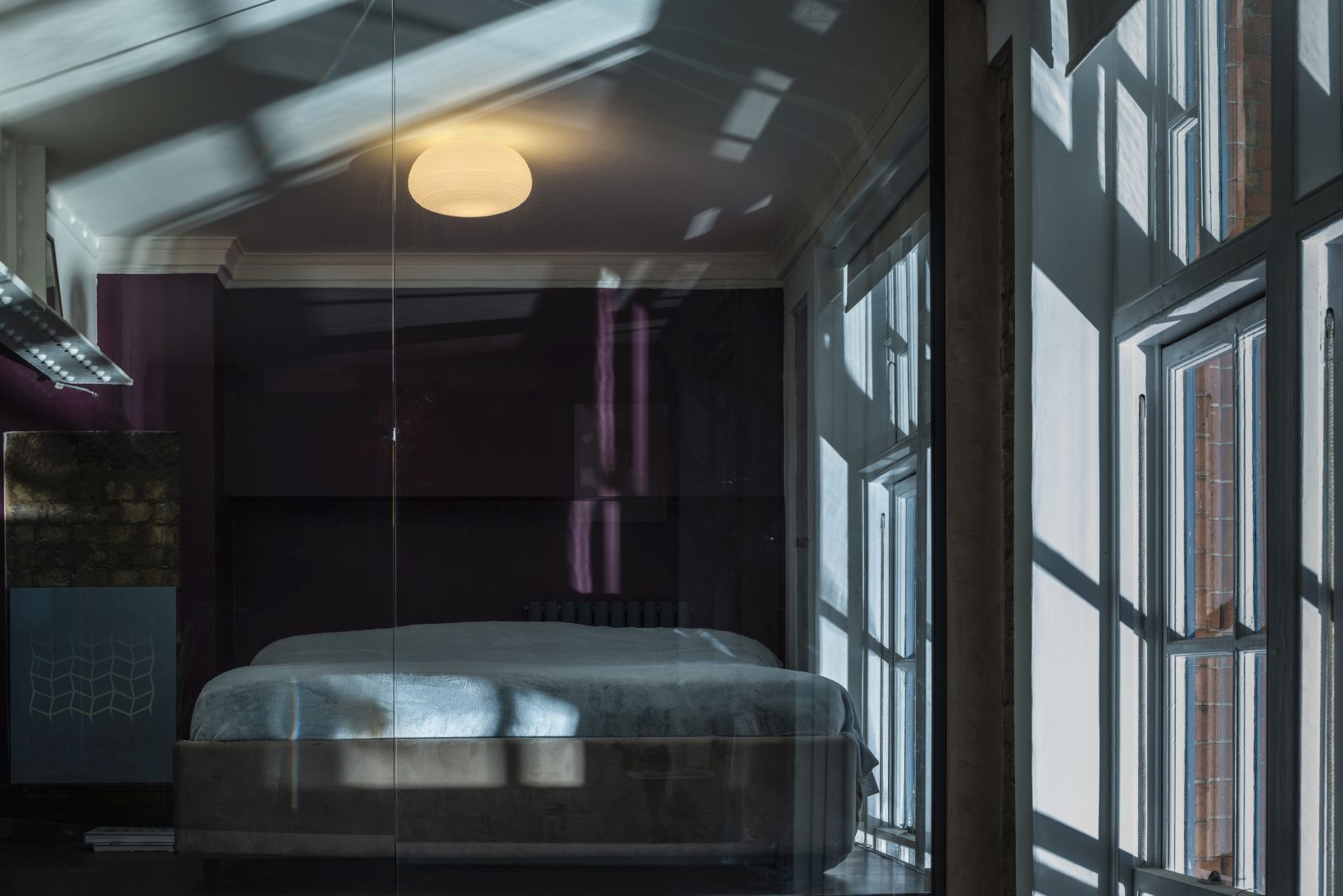 Rituals 2 Deckenleuchte von Foscarini über einem Bett in einem Schlafzimmer mit Fenster und Tageslicht.