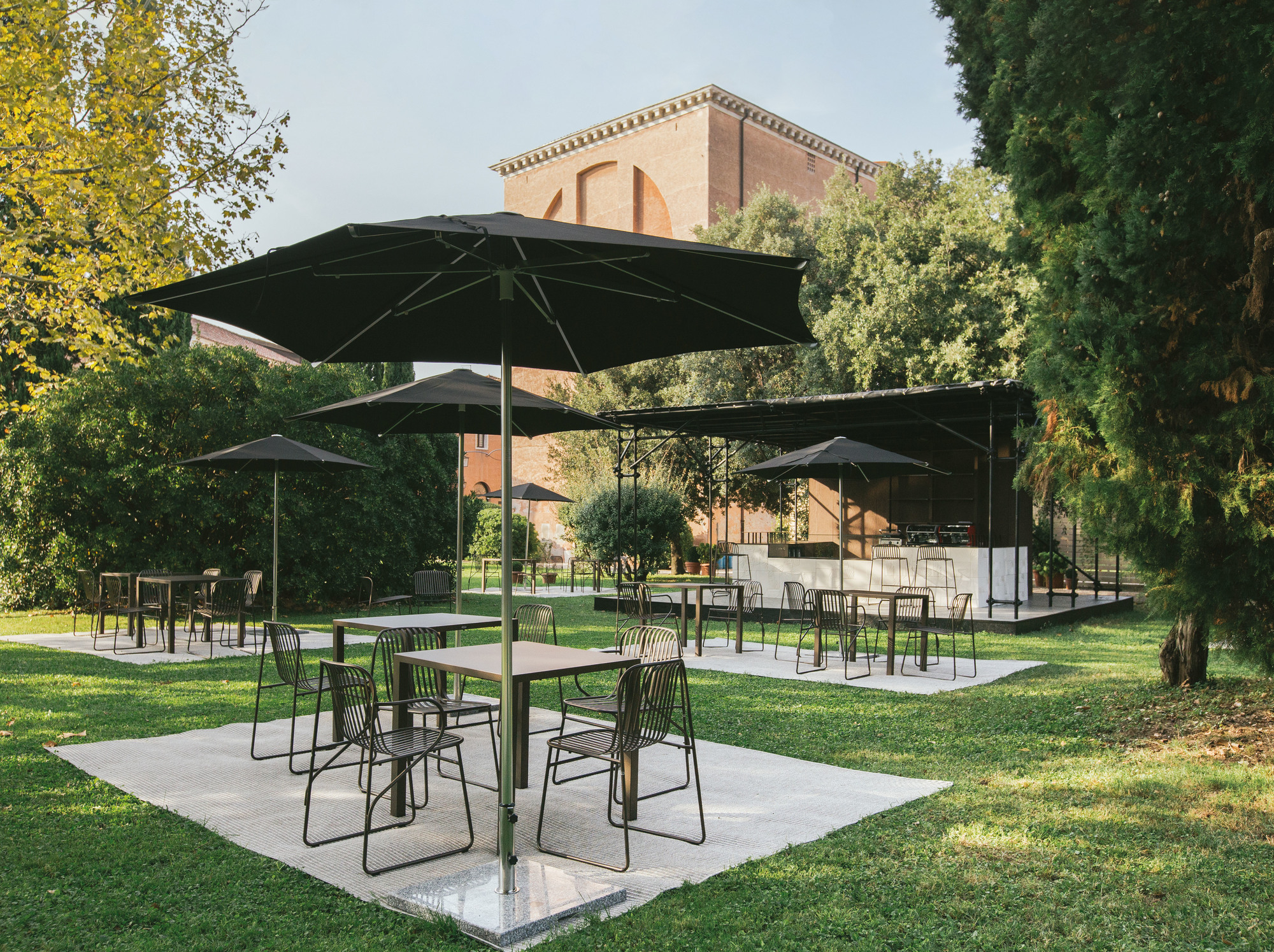 Riviera Stuhl Antikes Eisen von Emu, Gartenmöbel-Set mit Tischen und Stühlen auf Rasenfläche.