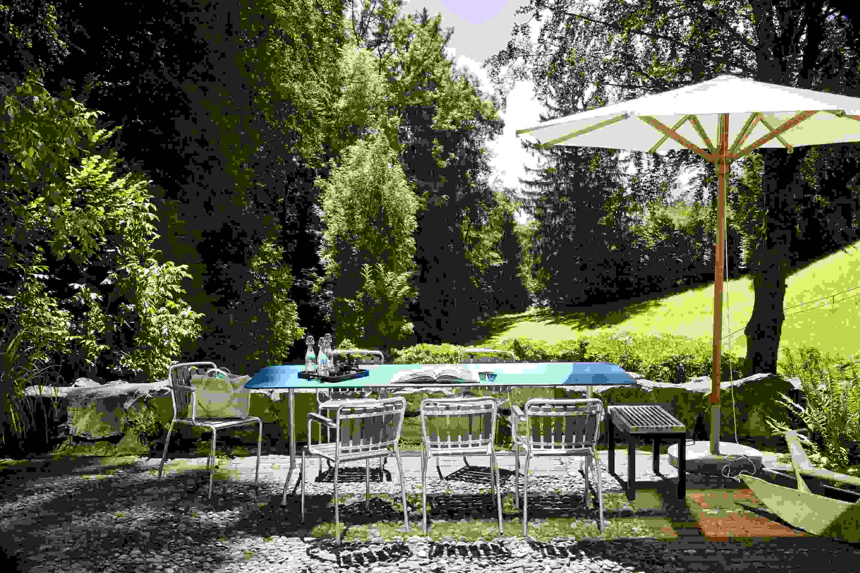 Haefeli Esstisch Outdoor in Graphitschwarz mit Stühlen und Sonnenschirm im Garten. Gartentisch für den Außenbereich.