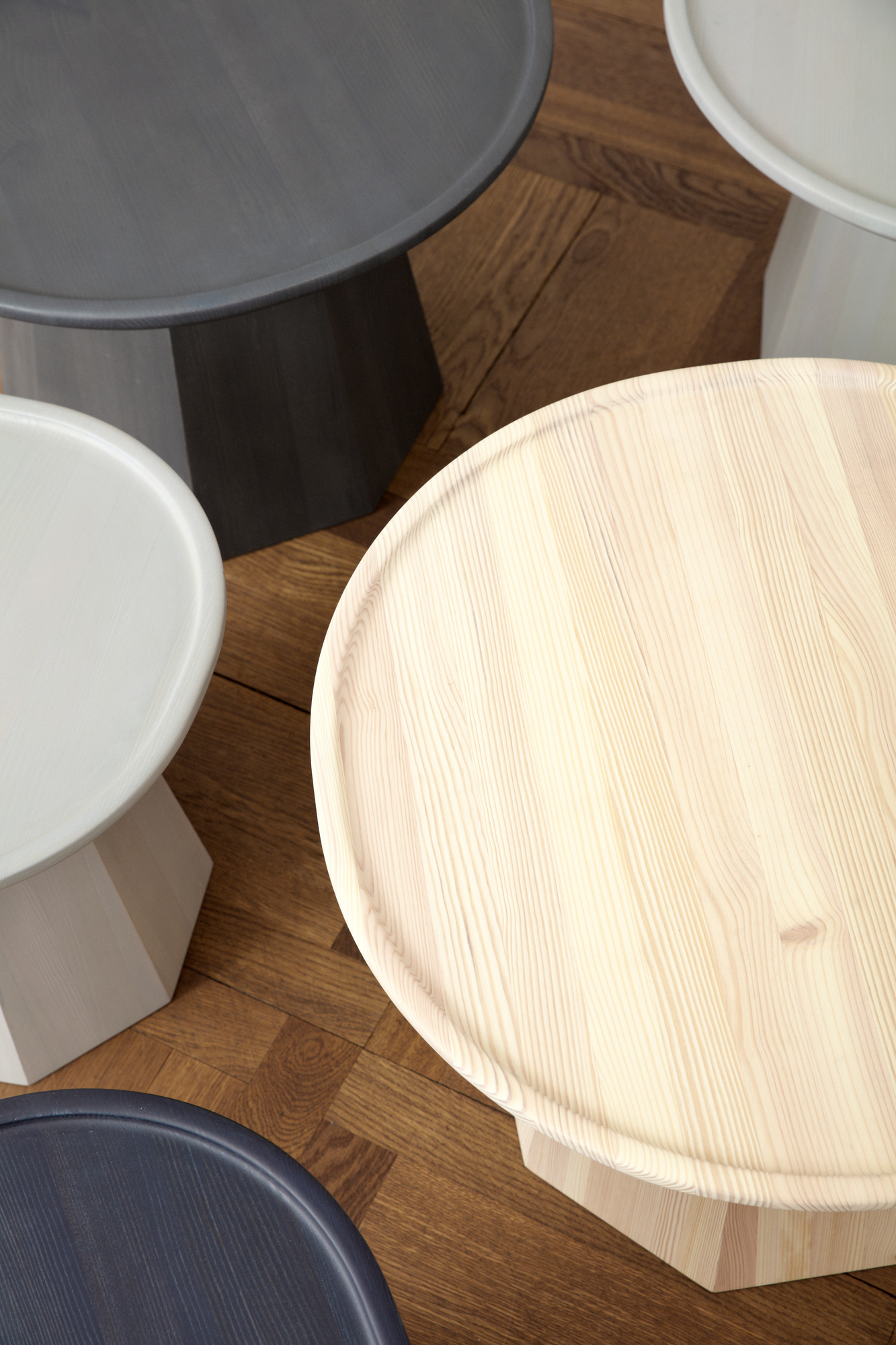 Ansicht von oben: Mehrere Normann Copenhagen Pine Table Beistelltische in verschiedenen Farben auf Parkettboden.