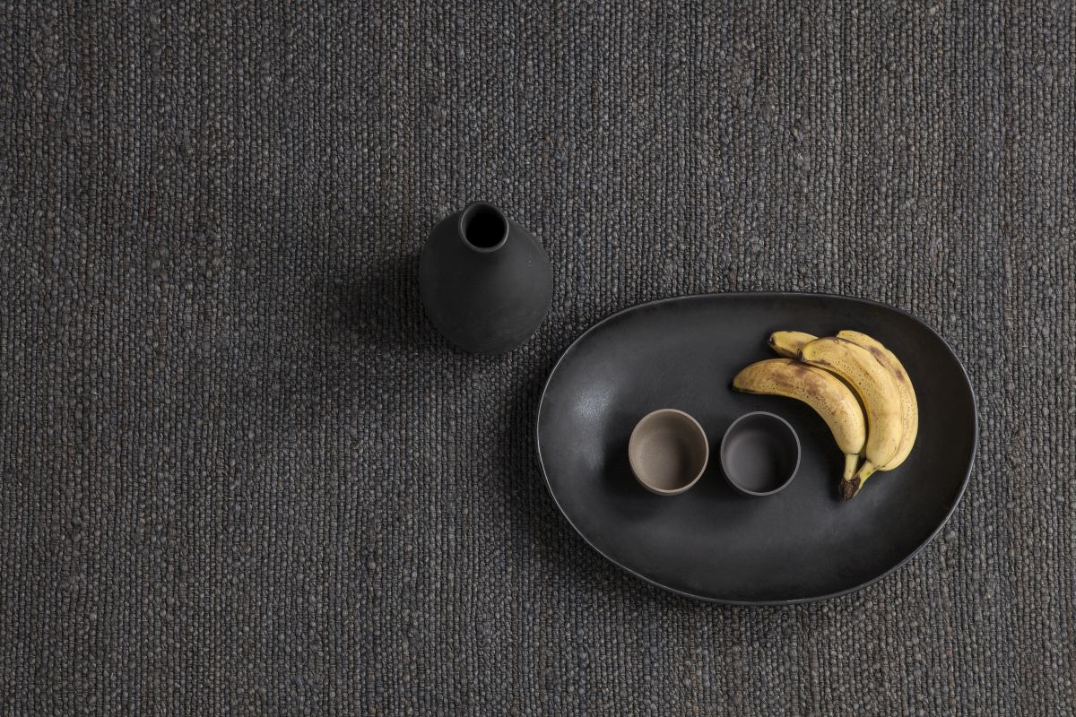 Nahaufnahme des grauen Nanimarquina Herb Teppichs mit Obstschale und Vase, Textur und Design.